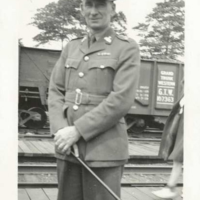 Photographie en noir et blanc – Archie prend la pose et sourit pour une photo dans son uniforme, devant un wagon.