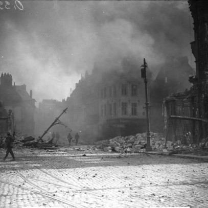 Photographie en noir et blanc – En face d’une place publique désertée et remplie de gravats, plusieurs soldats sont vus en train de marcher. La fumée envahit l’air.