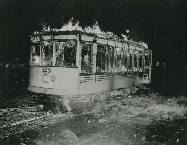 Photographie en noir et blanc – Une voiture de tramway brûle dans la nuit.